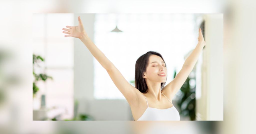リビング ルームで深呼吸する美しいアジアの若い女性