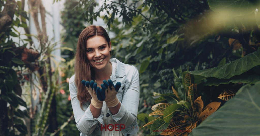 "植物に囲まれた庭でガーデニングを楽しむ女性|自然と触れ合うリラックスタイム"