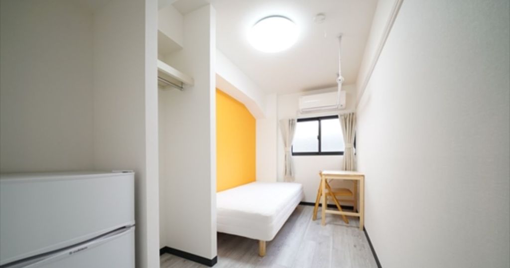 オレンジ色のアクセント壁があるシンプルな部屋の画像
