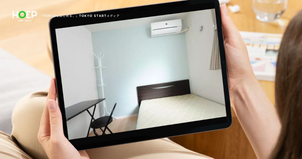 タブレットに表示されたベッドとデスクのある部屋を見ている写真
